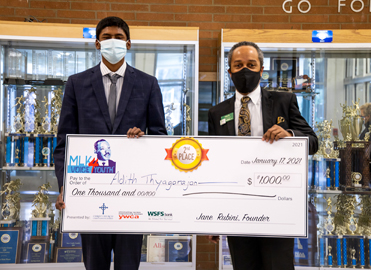 A WSFS Associate providing a giant check for $1,000 as the second prize in the MLK VOICE 4 YOUTH contest.