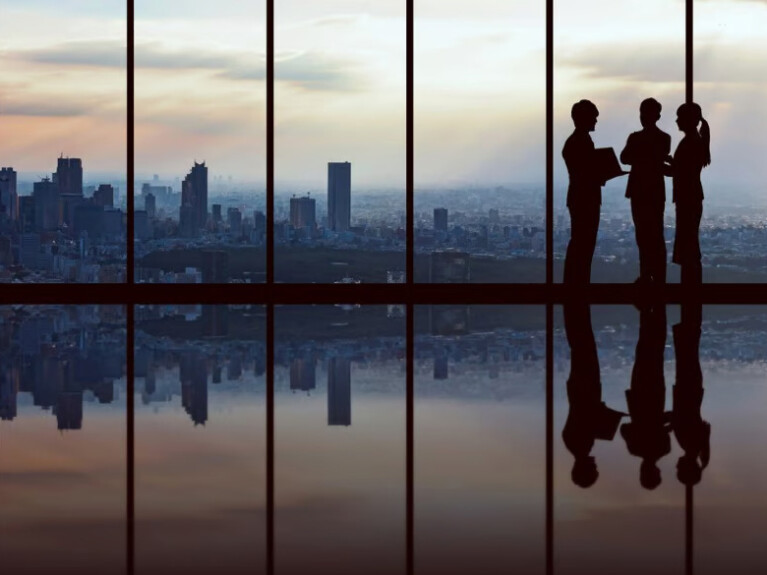 Business people standing silhouetted against a sunset.