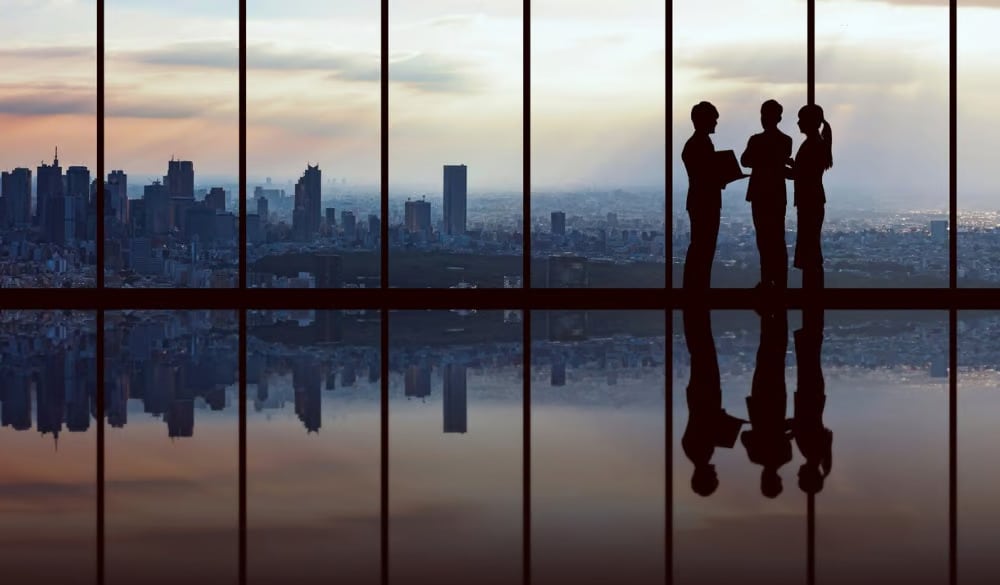 Business people standing silhouetted against a sunset.