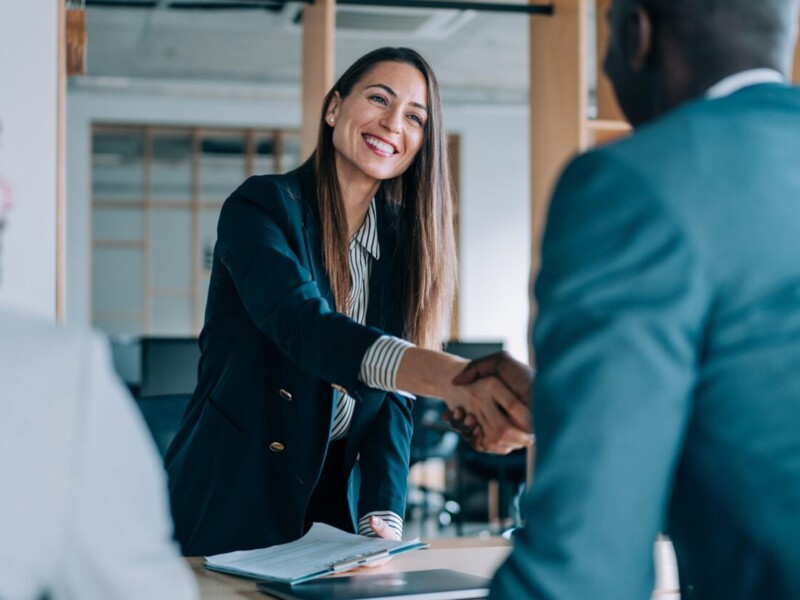 Businesspeople shaking hands over a conference table.