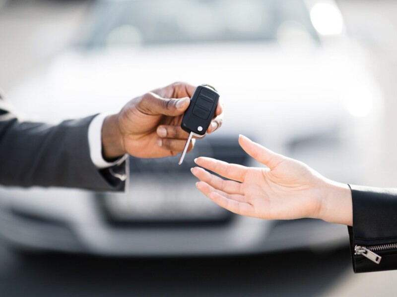 Car salesman handing over keys to new car.