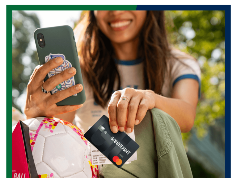 Woman holding Greenlight debit card