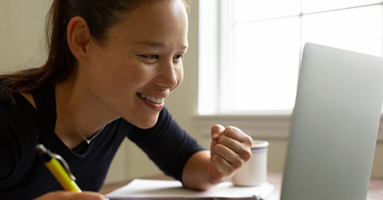 A woman smiling at her computer.