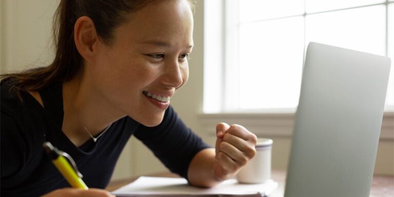 A woman smiling at her computer.