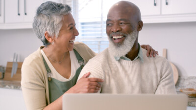 An older couple smiling in front of a computer.