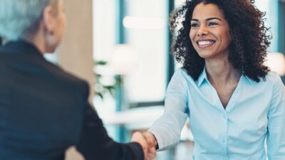 Two women smiling and shaking hands.