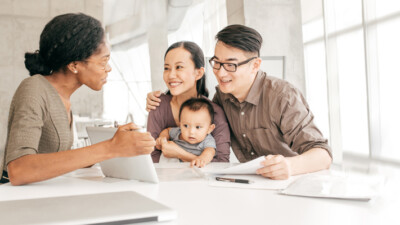 A woman showing a family something on a tablet screen.