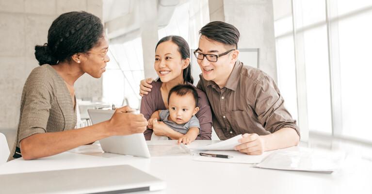 A woman showing a family something on a tablet screen.