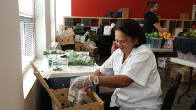 A woman filling a bag with green beans.