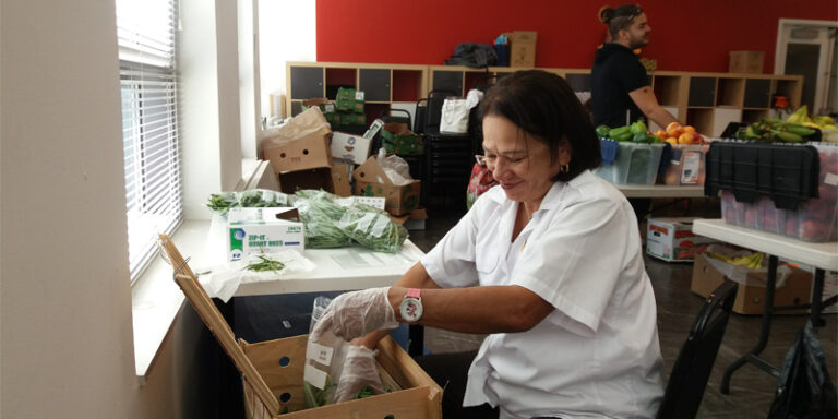 A woman filling a bag with green beans.