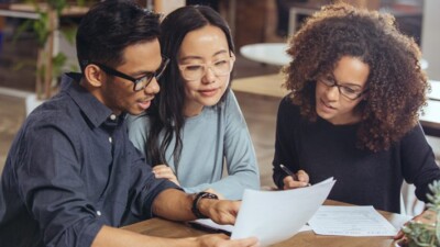 A man and two women reviewing documents.