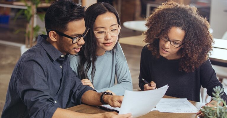 A man and two women reviewing documents.