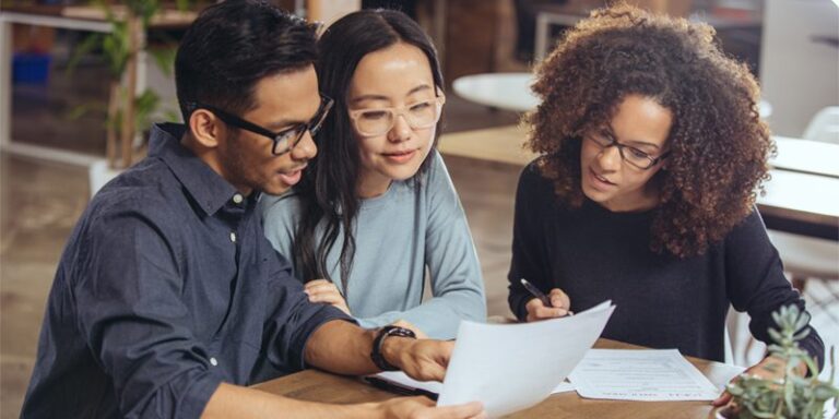 A man and two women reviewing documents.