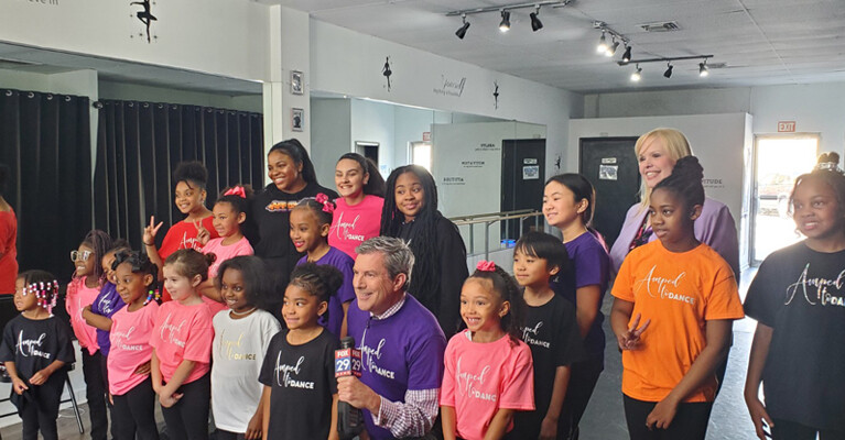 Fox 29 news anchor and WSFS Associate standing with students of Amped Dance Academy.