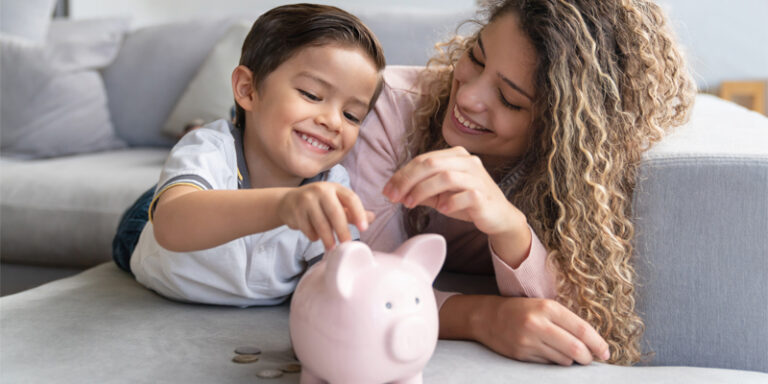 Child and woman putting coins into a piggy bank.