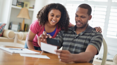 A child and a man digitally depositing a check.