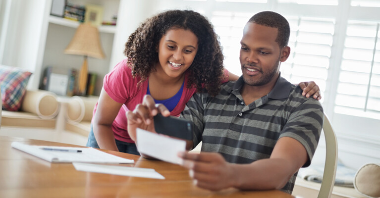 A child and a man digitally depositing a check.