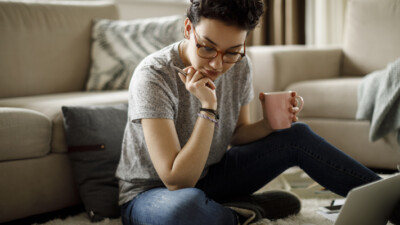 A student doing homework while holding a pink mug.