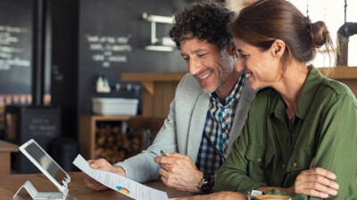A man and a woman reviewing paperwork at a cafe.
