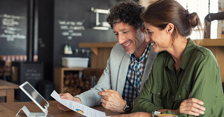 A man and a woman reviewing paperwork at a cafe.