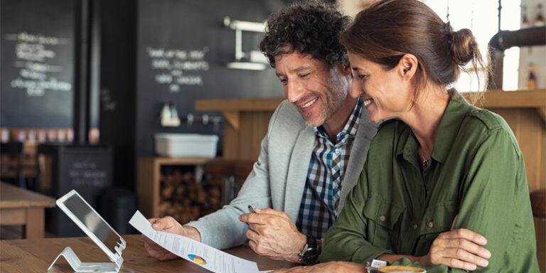 A man and a woman reviewing paperwork at a cafe.