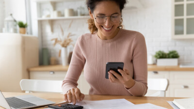 A woman using her cell phone and a calculator.