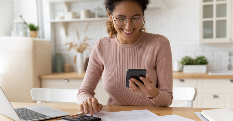 A woman using her cell phone and a calculator.