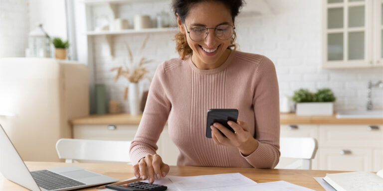 A woman using her cell phone and a calculator.