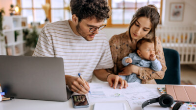 A young couple with their child working on revising their monthly budget.