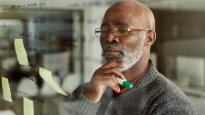 A man looking at notes on a whiteboard.