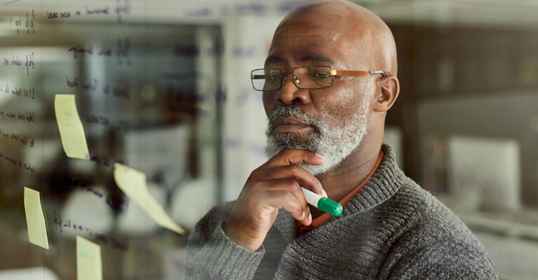 A man looking at notes on a whiteboard.