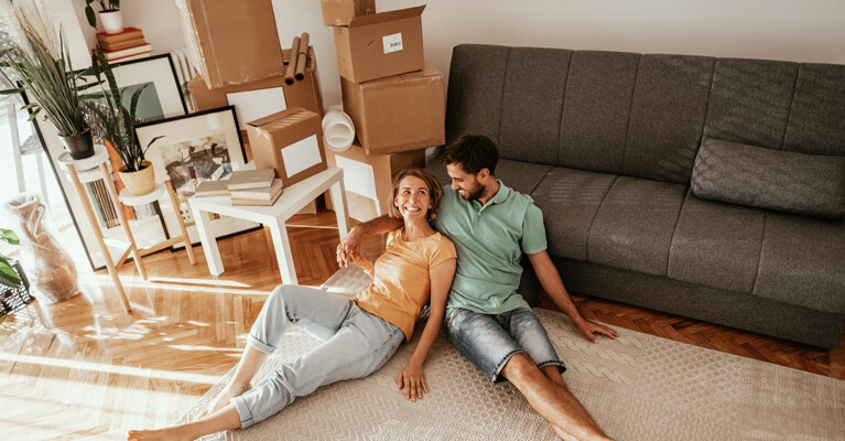 A couple relaxing amongst moving boxes in their new home.d