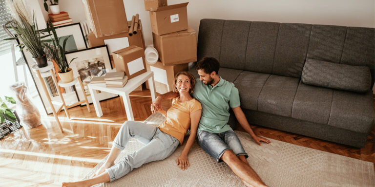 A couple relaxing amongst moving boxes in their new home.d