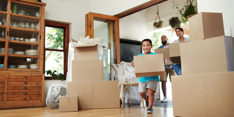 A family carrying boxes into their new house.