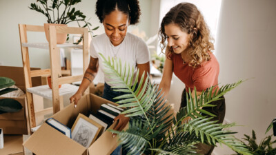 Two women unpacking boxes of books.