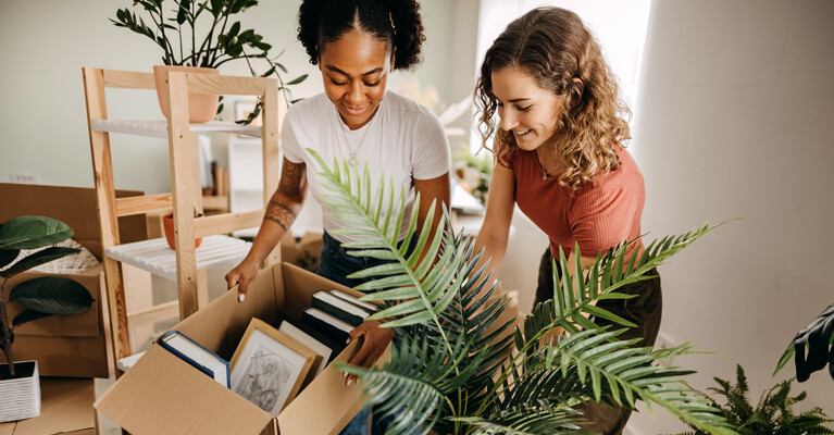 Two women unpacking boxes of books.