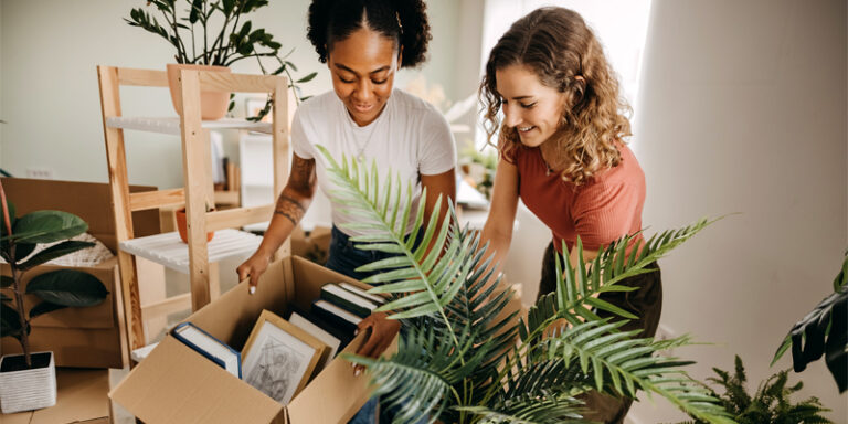 Two women unpacking boxes of books.
