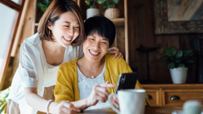 A mother and daughter looking at a cell phone.