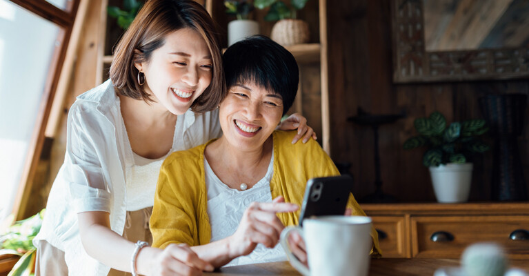 A mother and daughter looking at a cell phone.