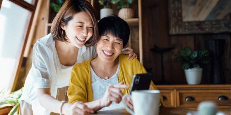 A mother and daughter looking at a cell phone.