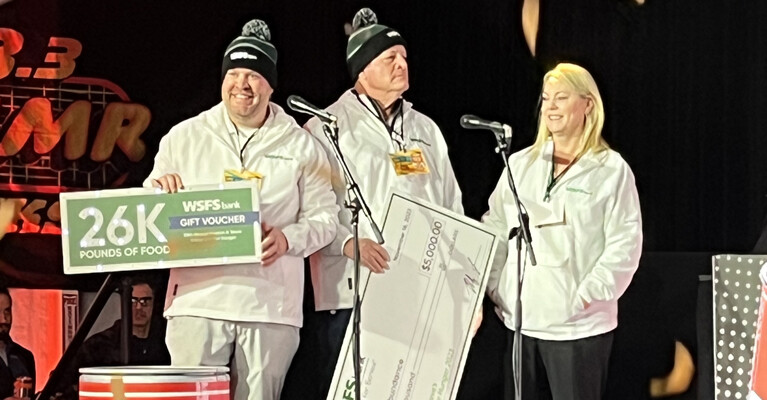 A photo of WSFS Bank Associates holding an oversized check for $5,000 and a voucher for 26,000 pounds of food to donate to Philabundance.