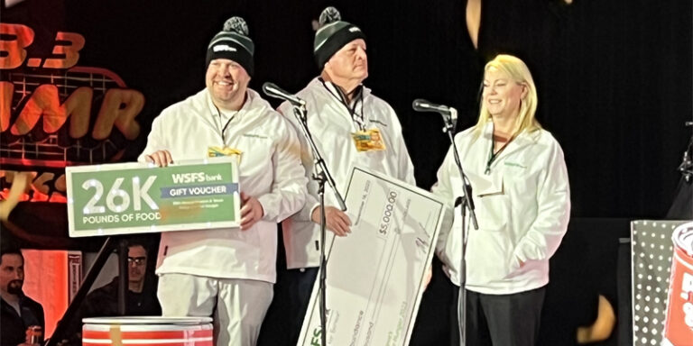 A photo of WSFS Bank Associates holding an oversized check for $5,000 and a voucher for 26,000 pounds of food to donate to Philabundance.