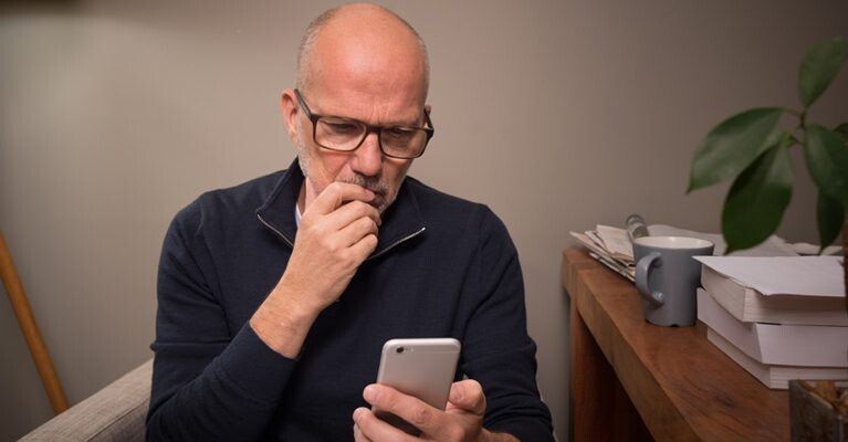 Man looking thoughtfully at cell phone.