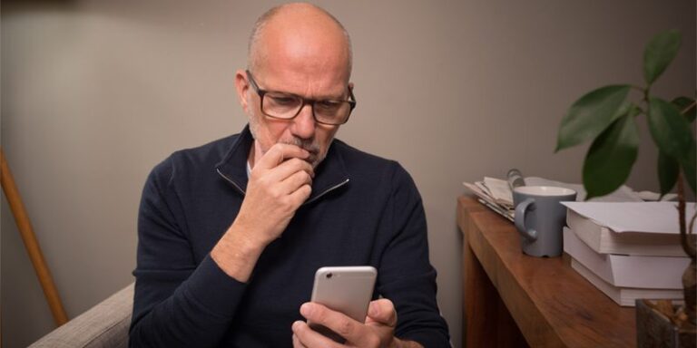 Man looking thoughtfully at cell phone.