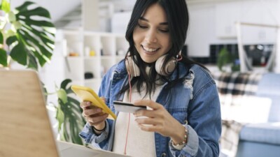 Woman using credit card and cell phone.