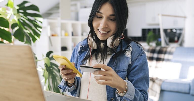 Woman using credit card and cell phone.