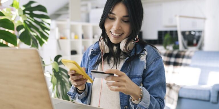 Woman using credit card and cell phone.