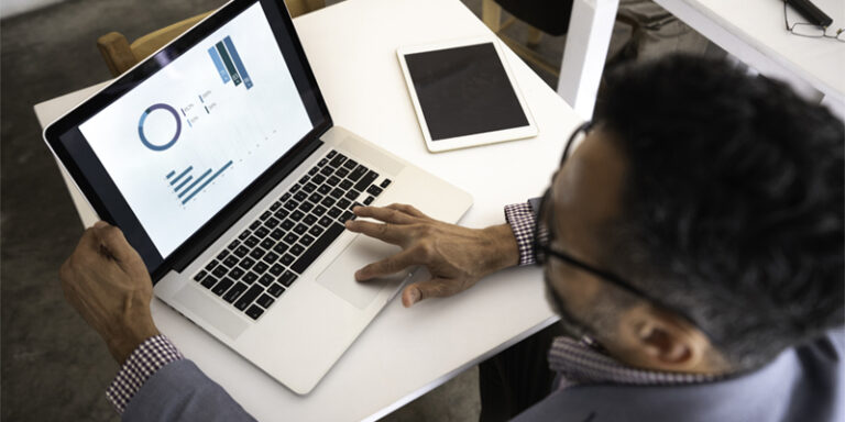 A man looking at charts on a laptop.
