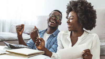 A man and a woman smiling while calculating their finances.