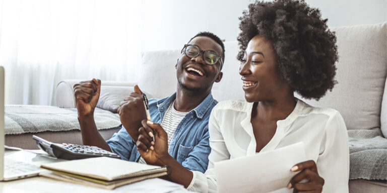 A man and a woman smiling while calculating their finances.